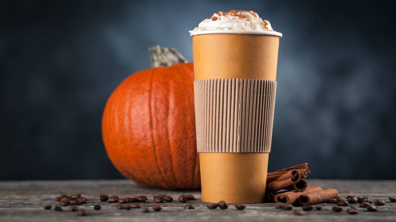 Pumpkin spice latte in a paper cup on dark background